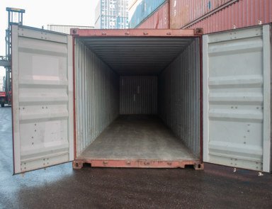 Interior of a used 40ft shipping container with the doors open, showing the long cargo space and worn floor